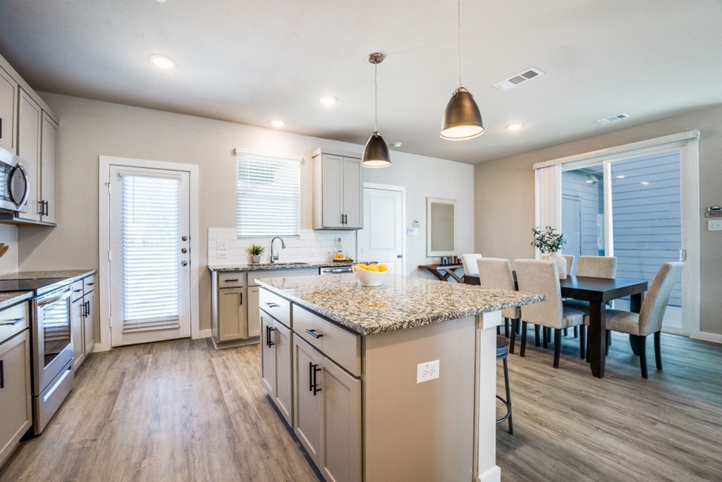 Canvas at Denton spacious kitchen with hardwood style flooring stainless steel appliances large island and granite countertops, build to rent, homes for rent in Denton, professionally managed rental home community, private yards, low maintenance, pet-friendly.