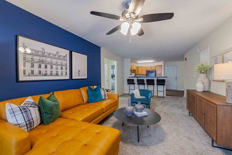 A living room with a yellow couch and a ceiling fan.