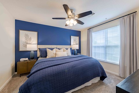 A bedroom with a bed, nightstands, and a ceiling fan.