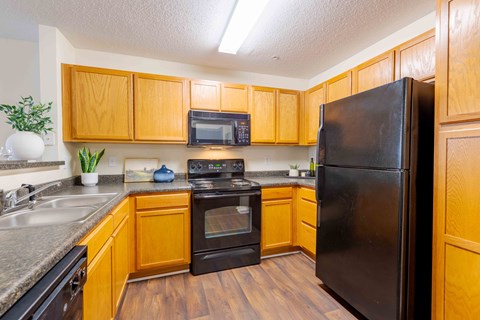 A kitchen with wooden cabinets and black appliances.