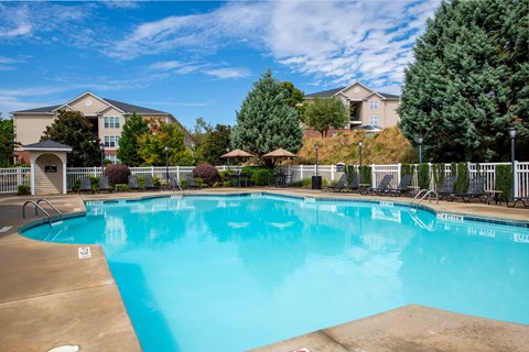 A large swimming pool in front of a building with a fence around it.