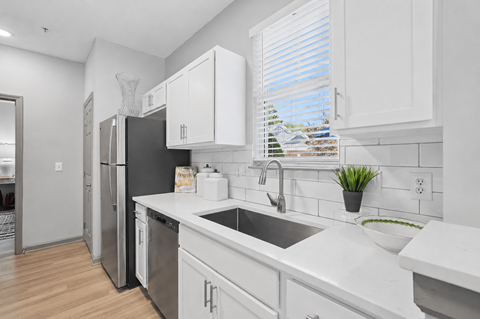 A kitchen with white cabinets and a black fridge.