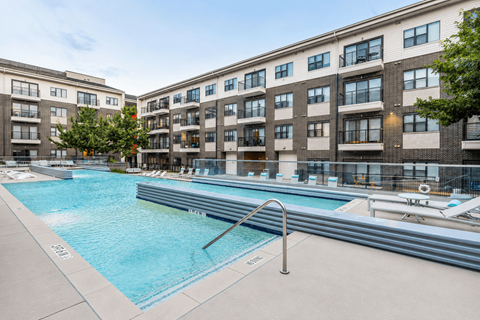 A swimming pool in front of a building with a metal ladder.