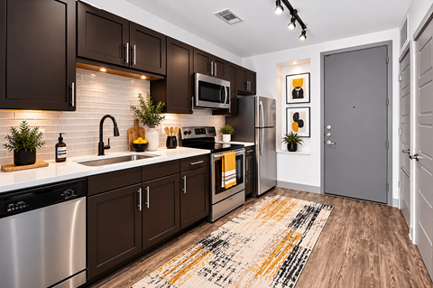 A modern kitchen with dark brown cabinets and a white backsplash.