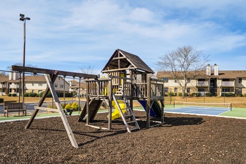 A playground with a swing set and a yellow slide.