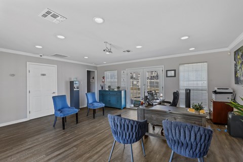 a lounge area with blue chairs and a coffee table