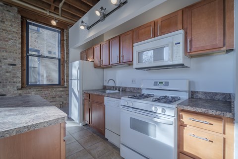 A kitchen with a white stove top oven and wooden cabinets.