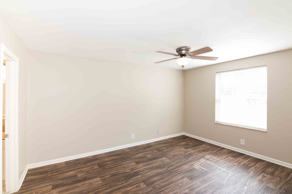 Apartments for Rent Murfreesboro - Condos at the Villager - Bedroom with Wood-Style Flooring, Window, and Lighted Ceiling Fan