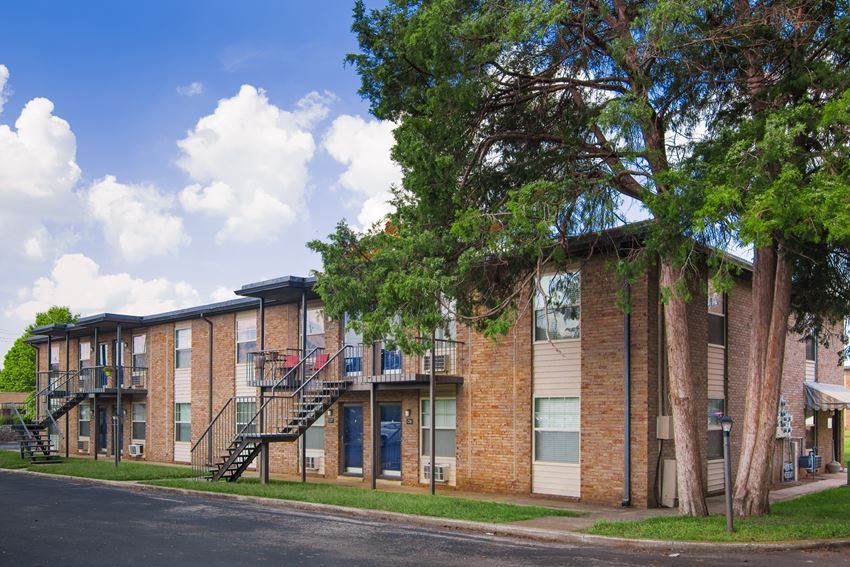 Exterior View of Condos at the Villager Apartments Building Sounded by Lush Landscaping