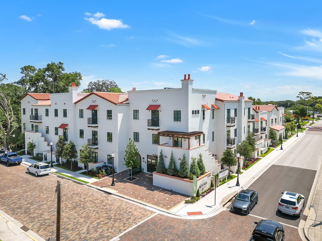an aerial view of a white building with cars parked in front of it