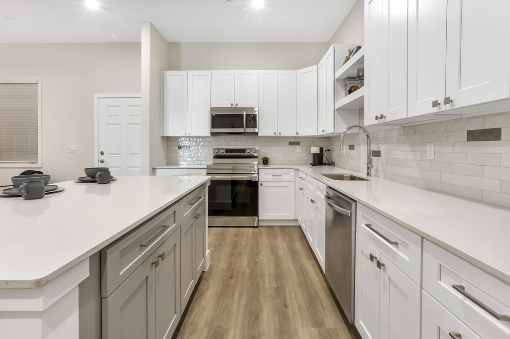 a large white kitchen with white counter tops and stainless steel appliances