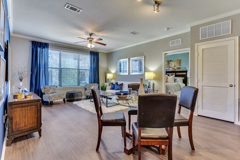 A dining room with a table set for two and a couch in the background.