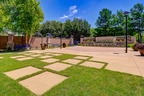 A park with a green lawn and a concrete walkway.