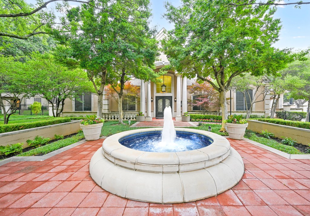 a fountain in a courtyard with a house in the background