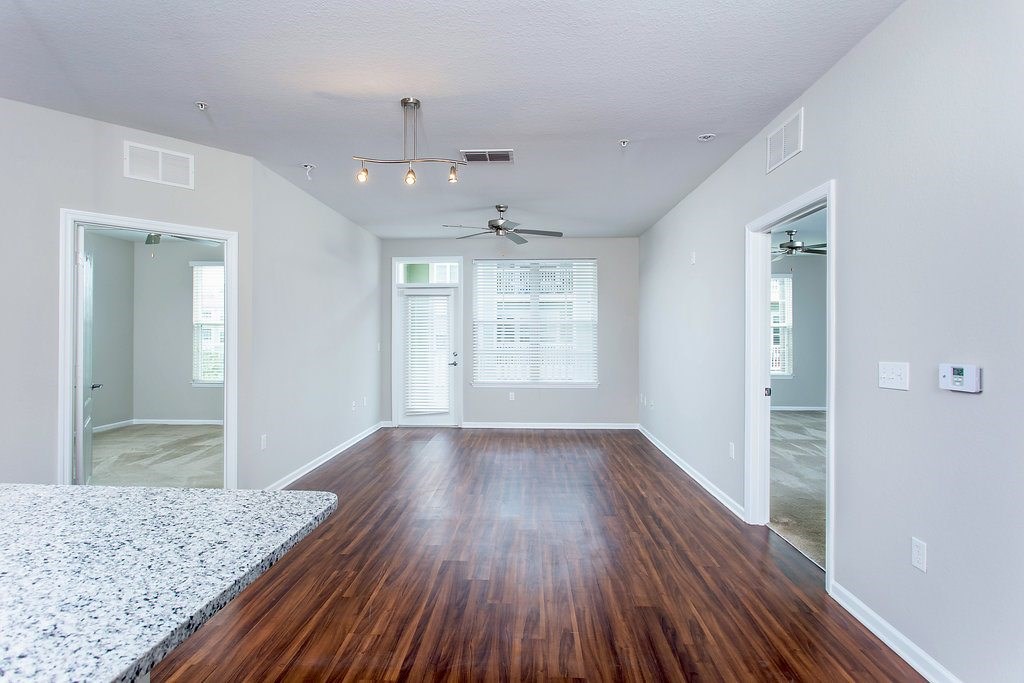 an empty living room with wood flooring and a ceiling fan