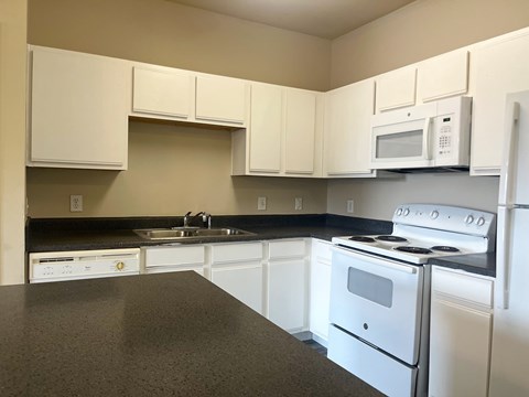 A kitchen with white appliances and cabinets.