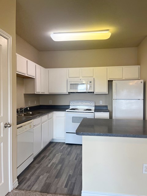 A kitchen with white cabinets and a black countertop.
