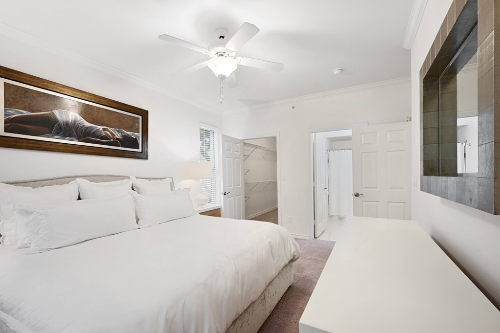 a white bedroom with a large bed and a ceiling fan