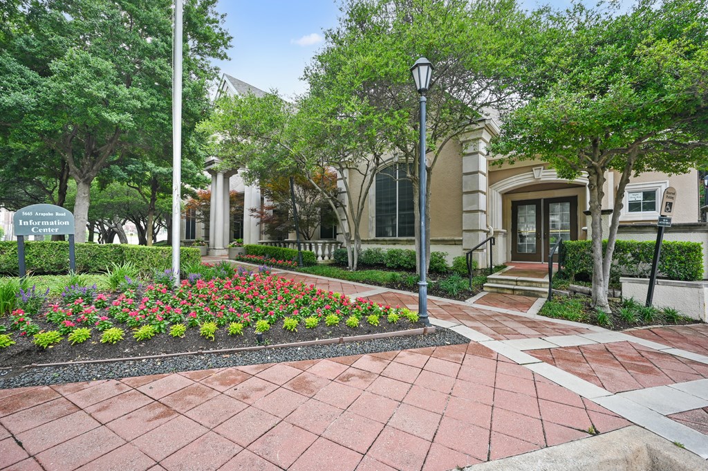 a courtyard with flowers and trees in front of a building