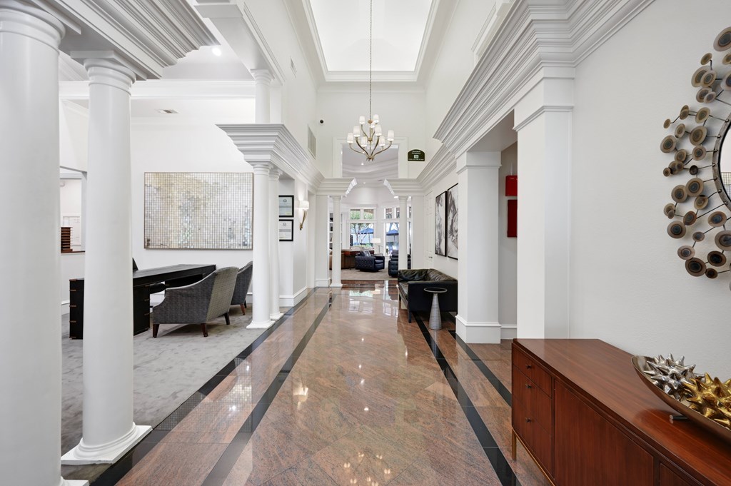 a long hallway with white pillars and a marble floor