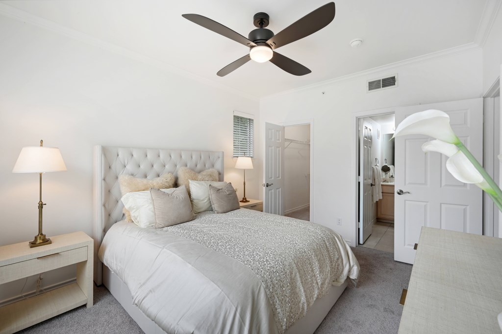 a white bedroom with a bed and a ceiling fan