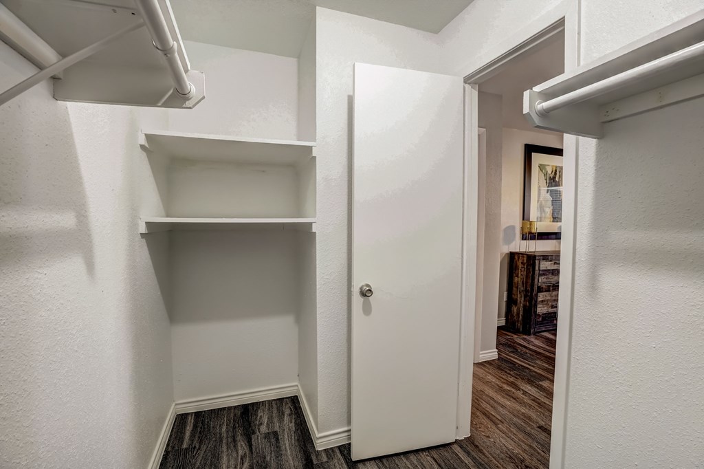 a closet in a bedroom with shelves and a door