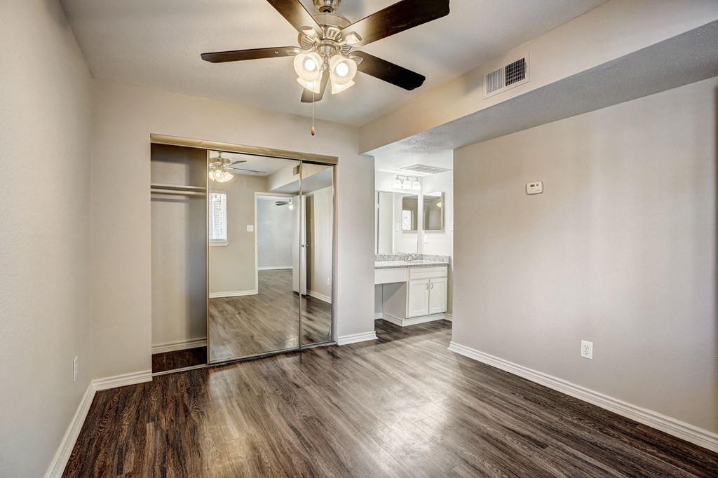 an empty living room with a ceiling fan and a kitchen
