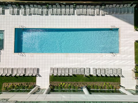 A rectangular pool with a white tiled wall and a white bench with a black back.