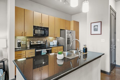 A kitchen with a black counter top and wooden cabinets.
