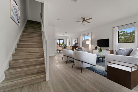 a living room with a staircase and a couch and a tv