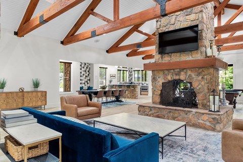 A living room with a stone fireplace and a blue couch.