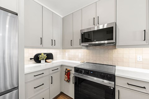 A kitchen with white cabinets and a black oven.