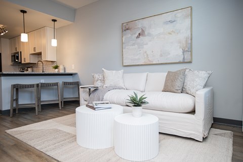 A living room with a white couch and a painting on the wall.