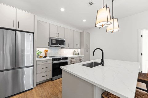 A modern kitchen with a white marble countertop and stainless steel appliances.