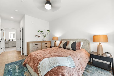A bedroom with a bed, nightstands, and a ceiling fan.