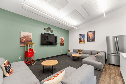 A living room with a grey couch, a wooden table, and a television on the wall.