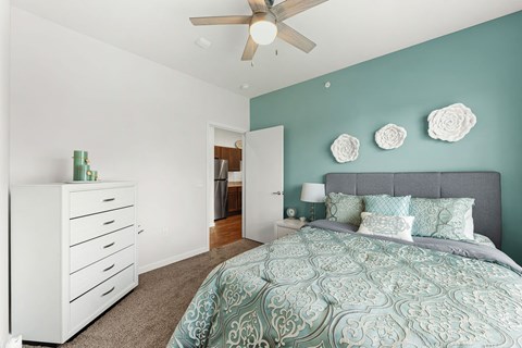 A bedroom with a bed, dresser, and ceiling fan.