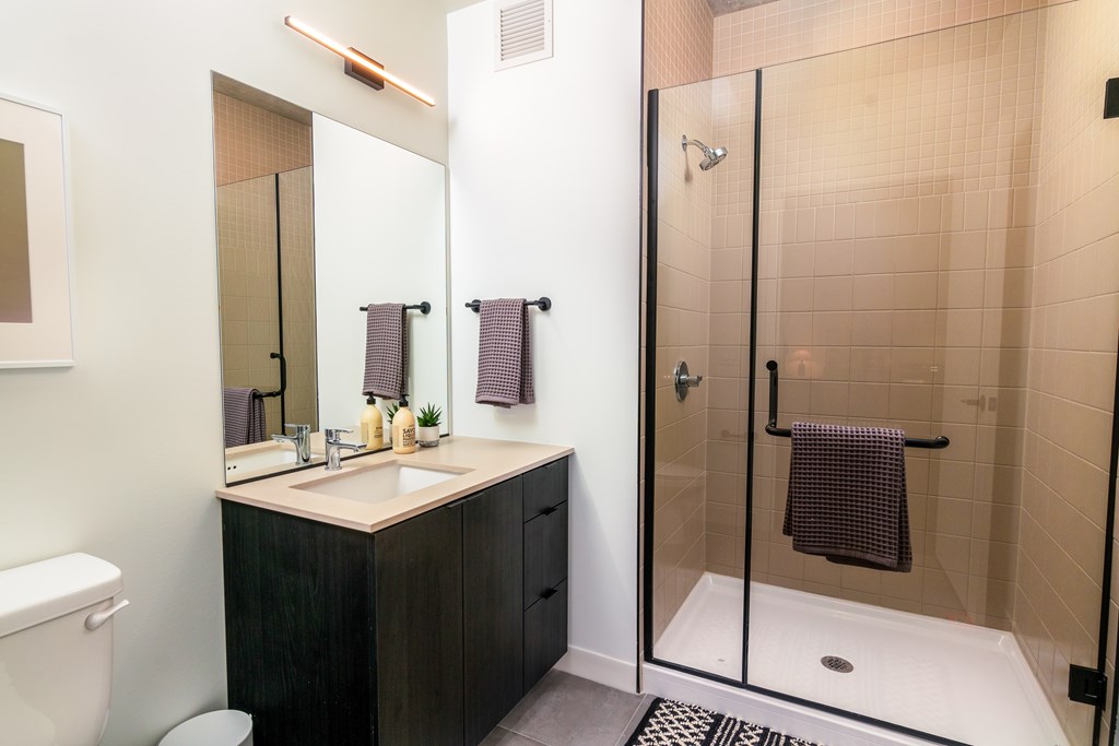 a bathroom with a shower sink and mirror and a toilet