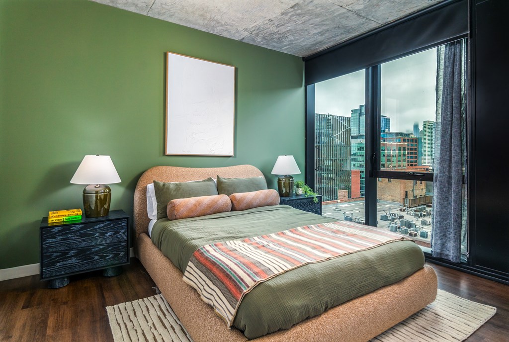 a bedroom with green walls and a large window and a bed