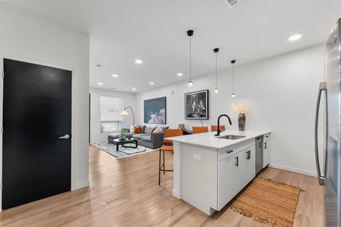 A modern kitchen with a black door and a wooden floor.