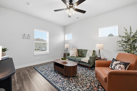 A living room with a brown couch, a coffee table, and a ceiling fan.