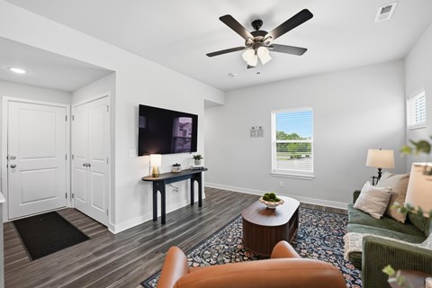 A living room with a ceiling fan and a television on the wall.