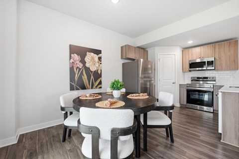 A dining room with a table set for two and a kitchen in the background.