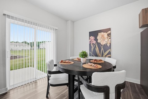 A dining room with a table set for two and a view of a parking lot outside.