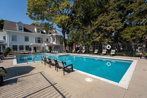 a swimming pool with chairs and a building in the background