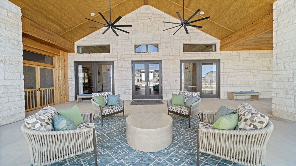 a covered patio with couches and chairs and two chandeliers