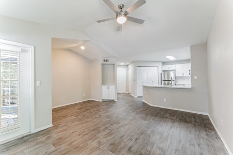 A spacious room with a ceiling fan and wooden flooring.