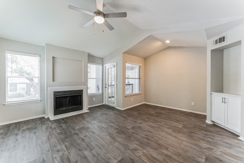 A spacious living room with a fireplace and hardwood floors.