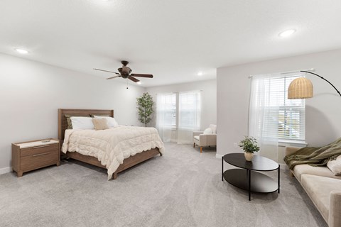 A bedroom with a large bed, a couch, and a ceiling fan.