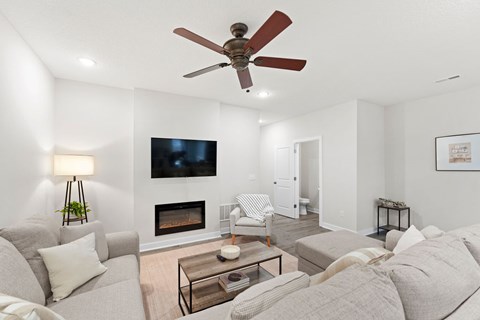 A living room with a grey couch, a fireplace, and a television mounted on the wall.